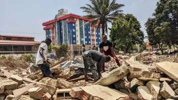 Des hommes récupèrent des métaux sur le chantier de démolition de la cité ministérielle à Conakry